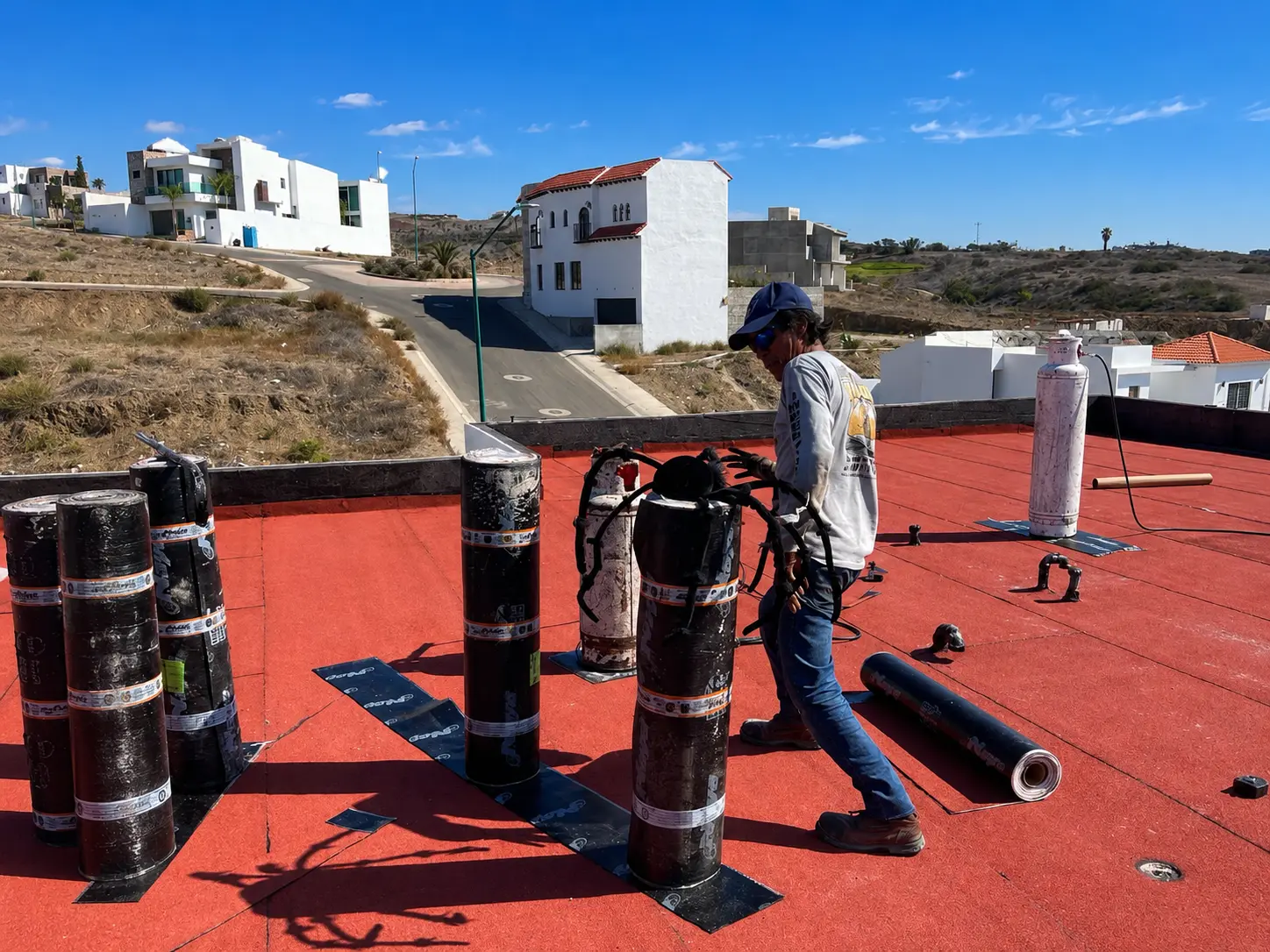 Rollos de manto asfáltico y tanques de gas en posición para el antorchado